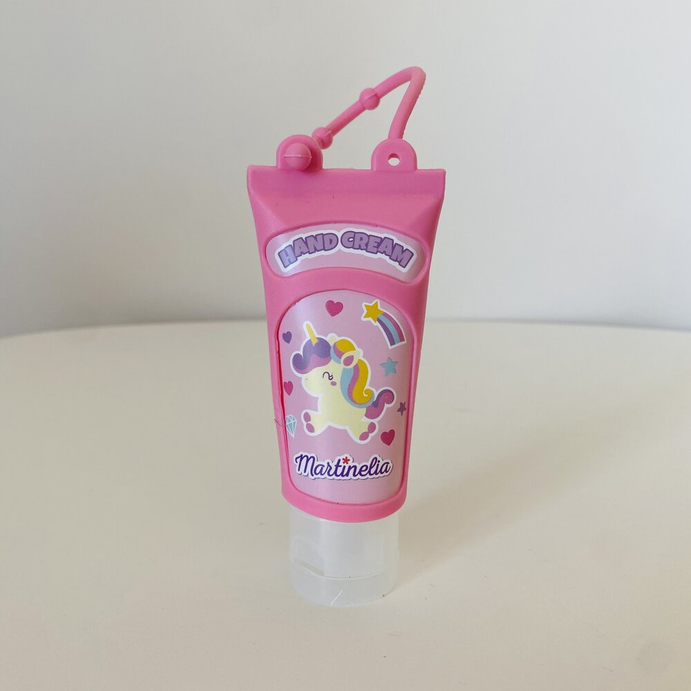 Creme de mãos rosa com desenho de unicórnio e texto 'HAND CREAM'.