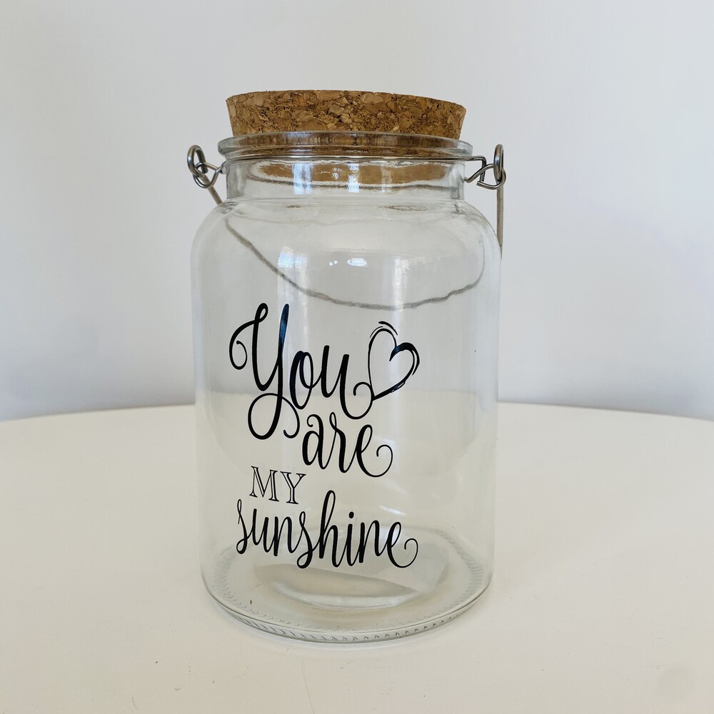 Frasco de vidro transparente com tampa de cortiça e texto decorativo