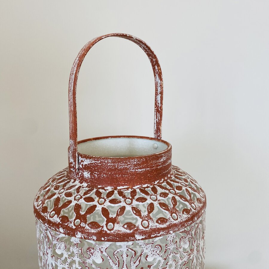Lanterna decorativa de metal com padrão floral recortado e alça superior