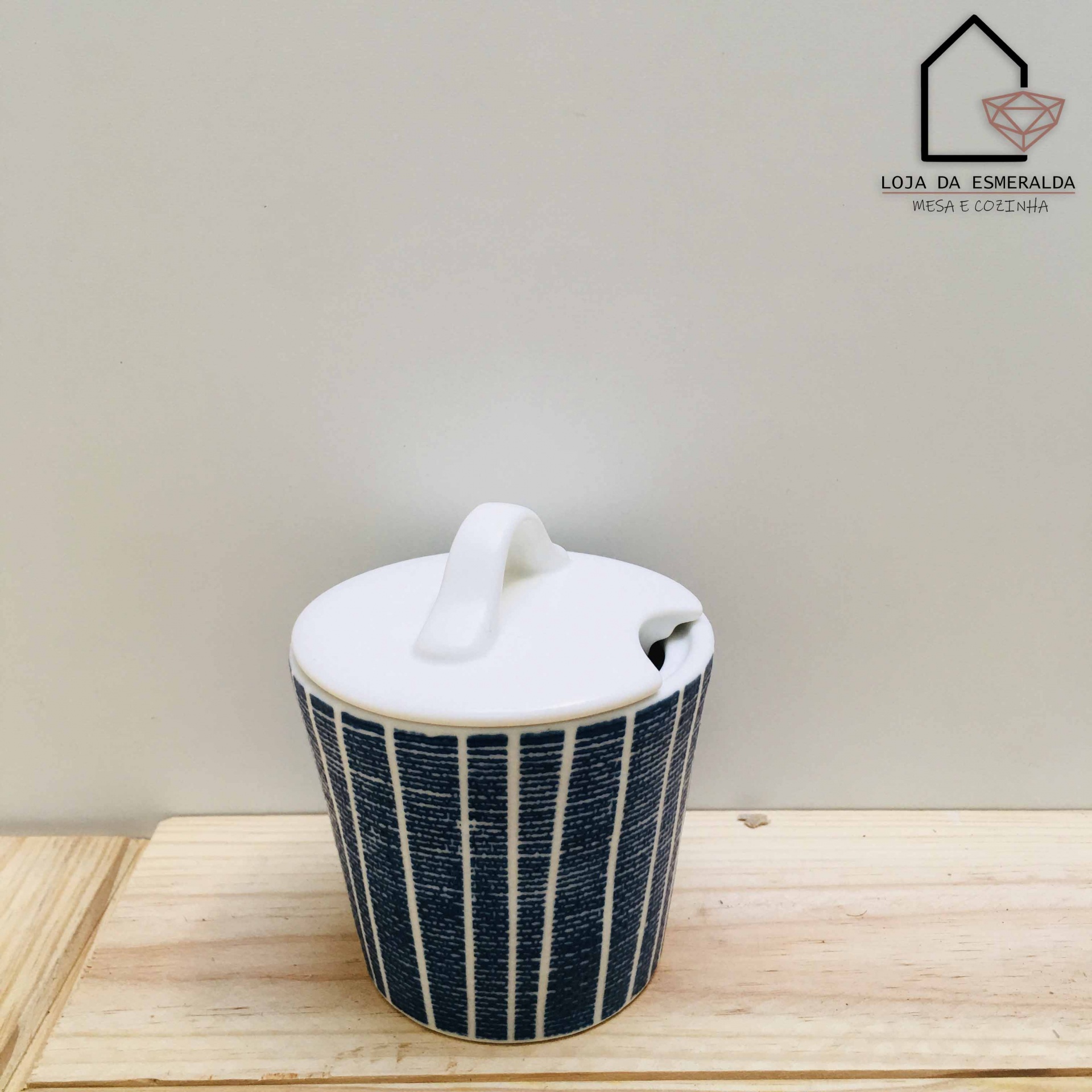 Frasco de cerâmica azul com tampa branca sobre mesa de madeira