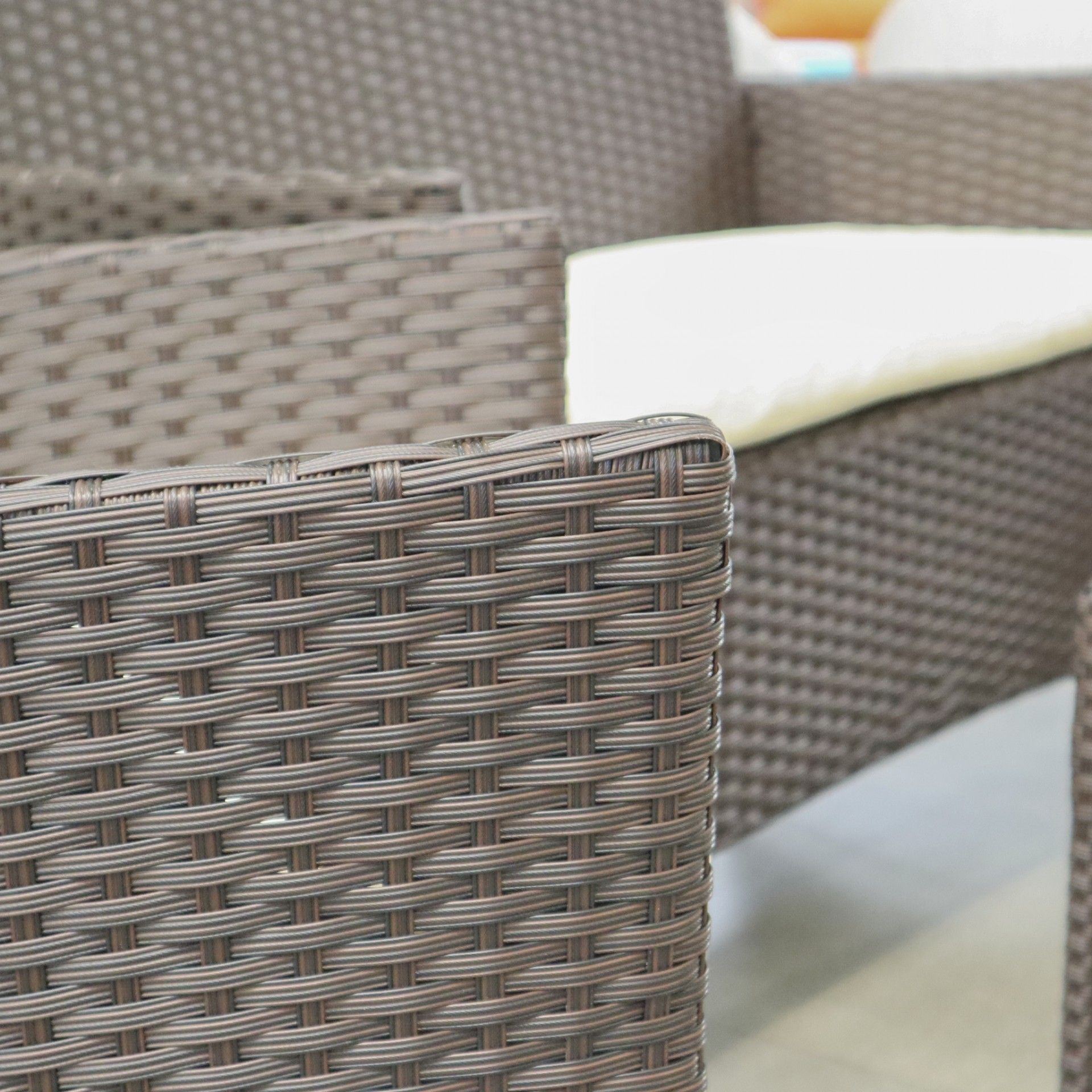 Cadeiras de material sintético trançado castanho com almofadas claras em interior