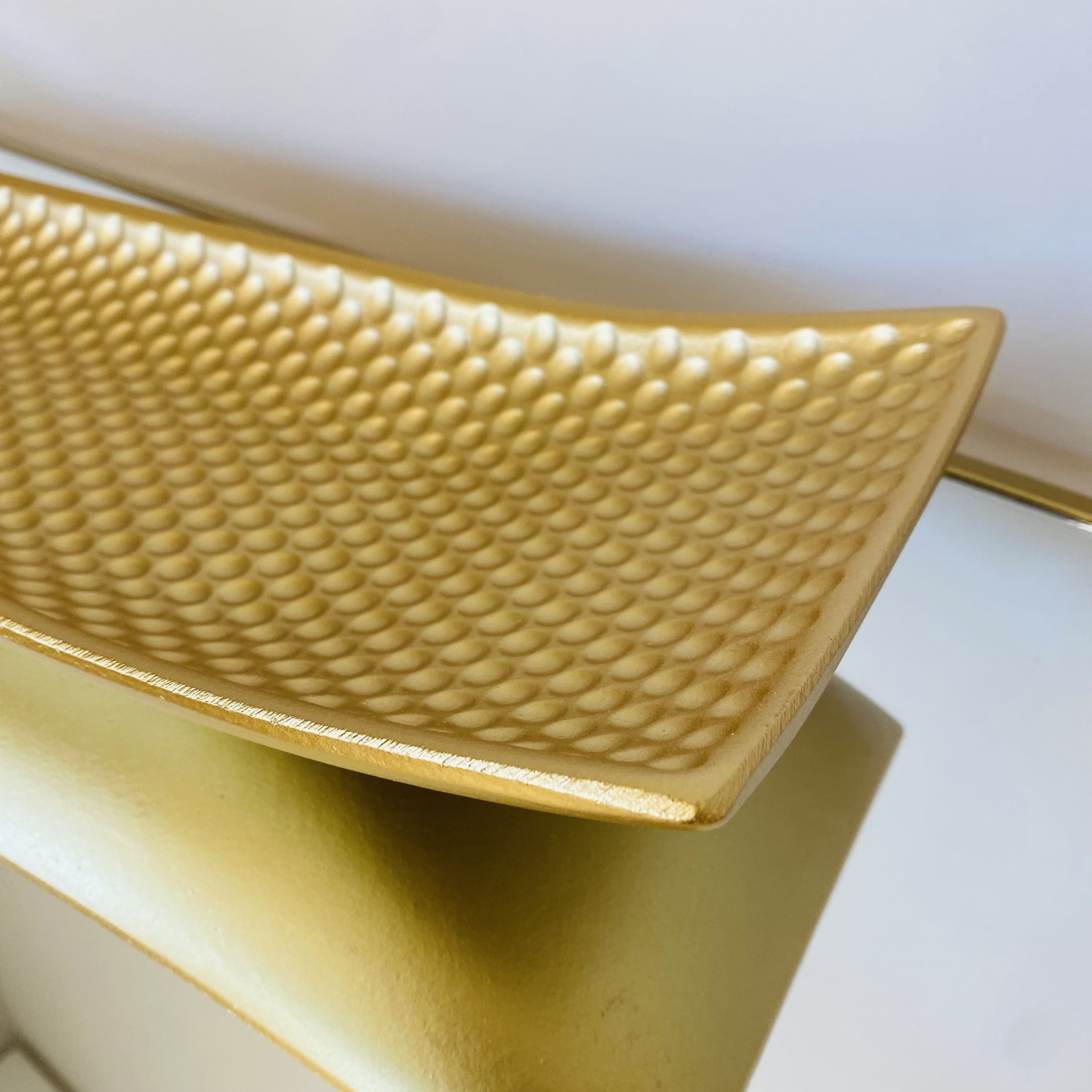 Prato retangular dourado com textura de bolhas arredondadas em fundo dourado