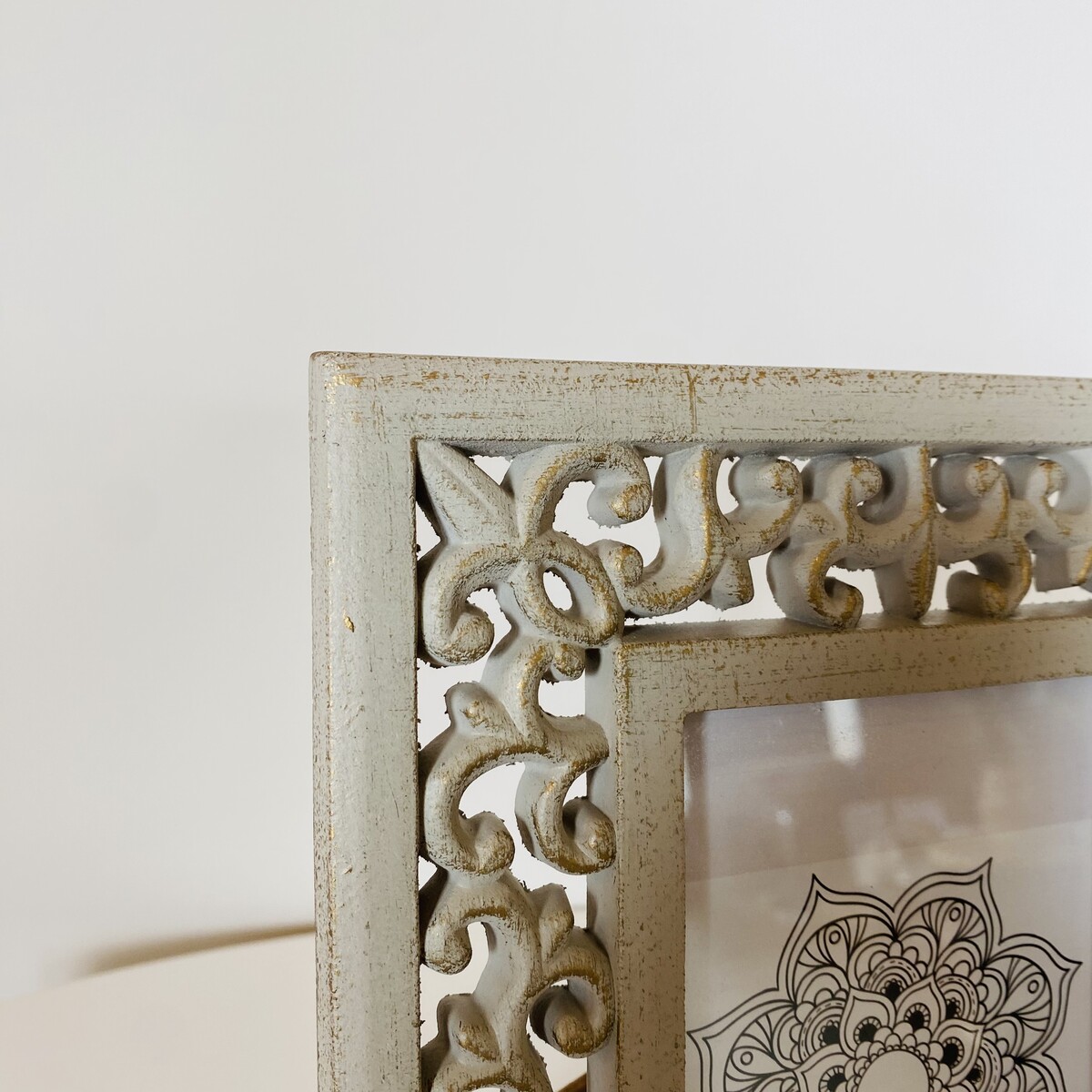 Moldura metal branca envelhecida com padrão ornamental e laço