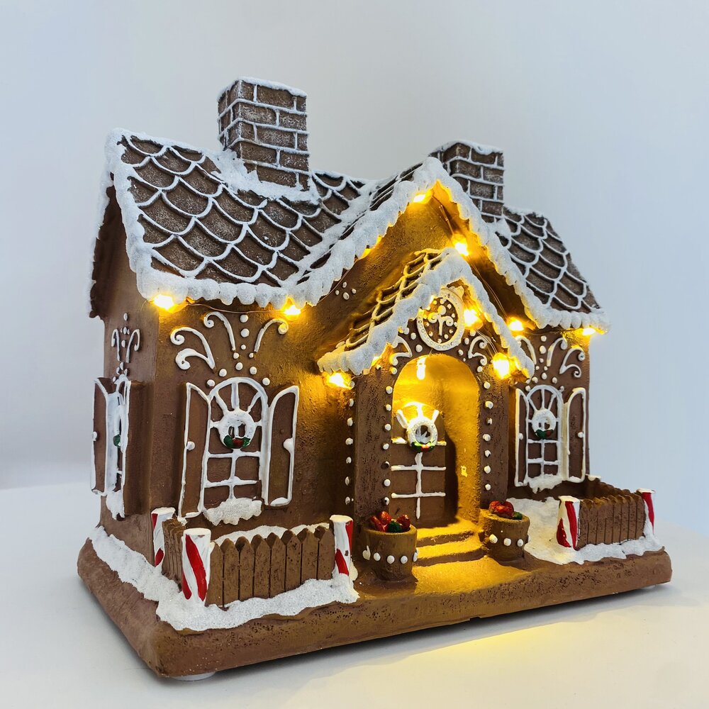 Casa decorativa de pão-de-espécie iluminada com detalhes em neve e doces