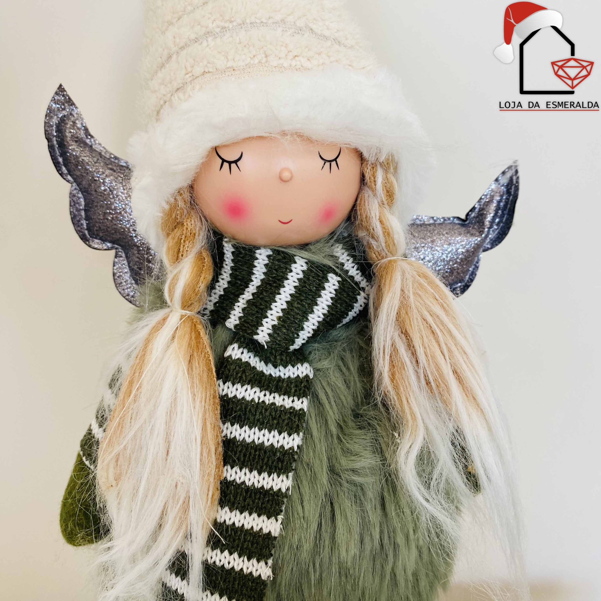 Boneca decorativa com cabelo loiro em tranças, chapéu branco, cachecol verde e branco, vestido verde e asas prateadas