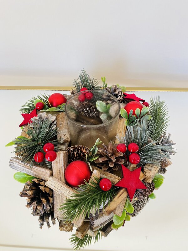 Arranjo decorativo natalício com madeira, pinhas, bagas vermelhas e copo de vidro no centro
