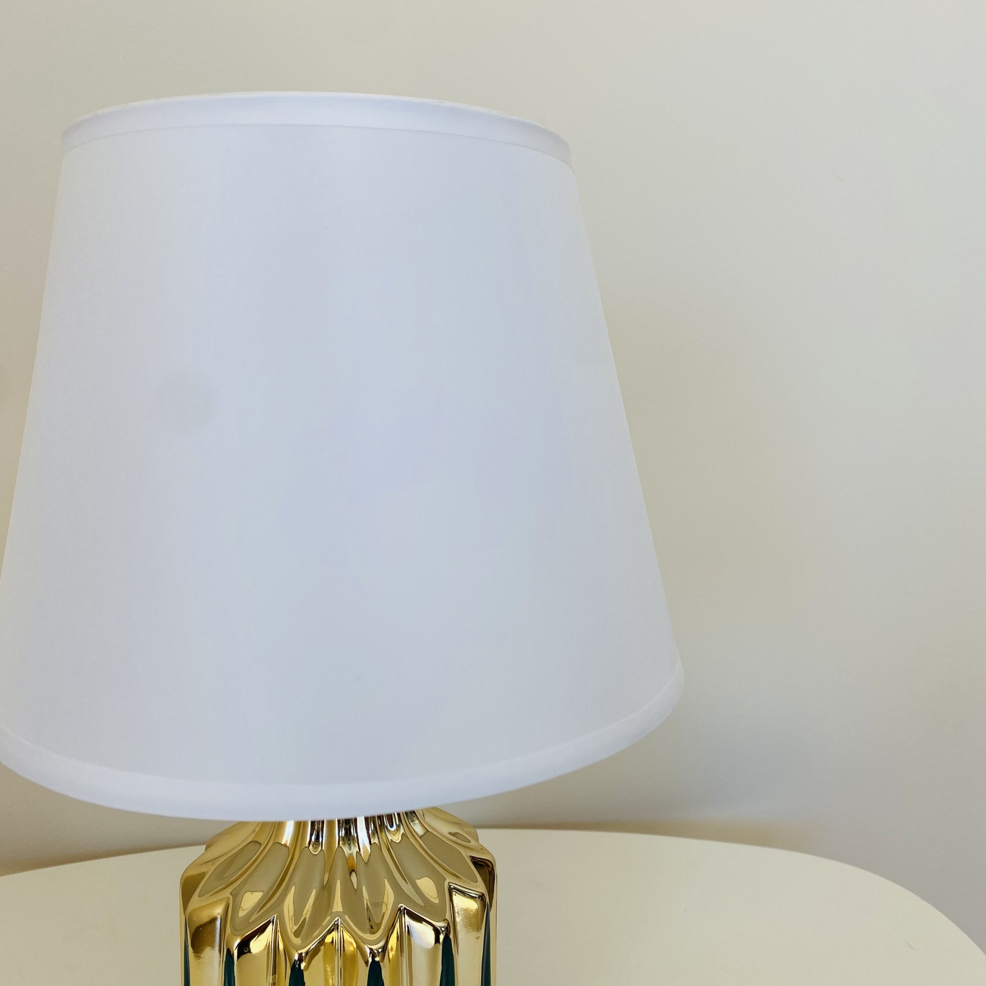 Lâmpada de mesa com abajur branco e base dourada texturizada em mesa branca