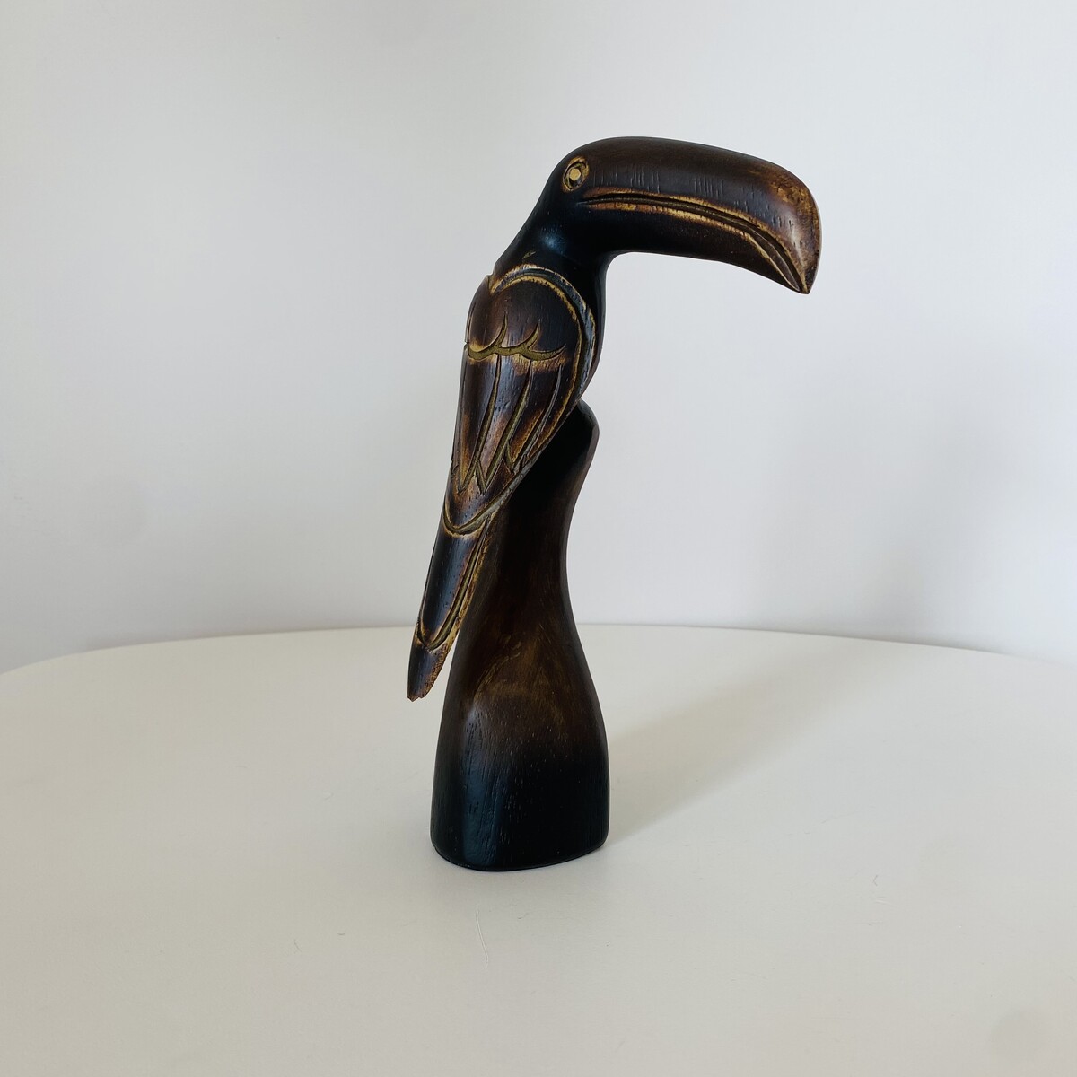 Estatueta de pássaro em madeira castanha escura com detalhes entalhados