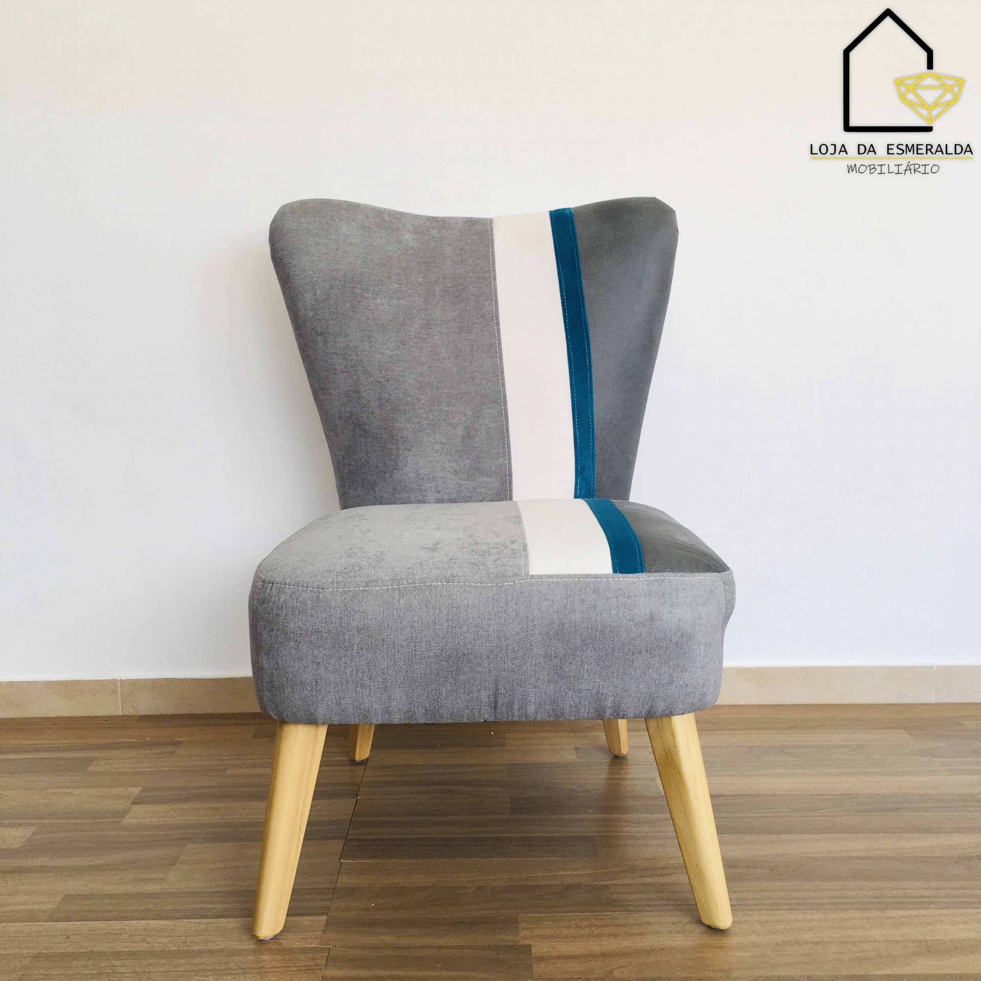 Cadeira cinza estofada com riscas brancas e azuis, pernas de madeira clara, em chão de madeira