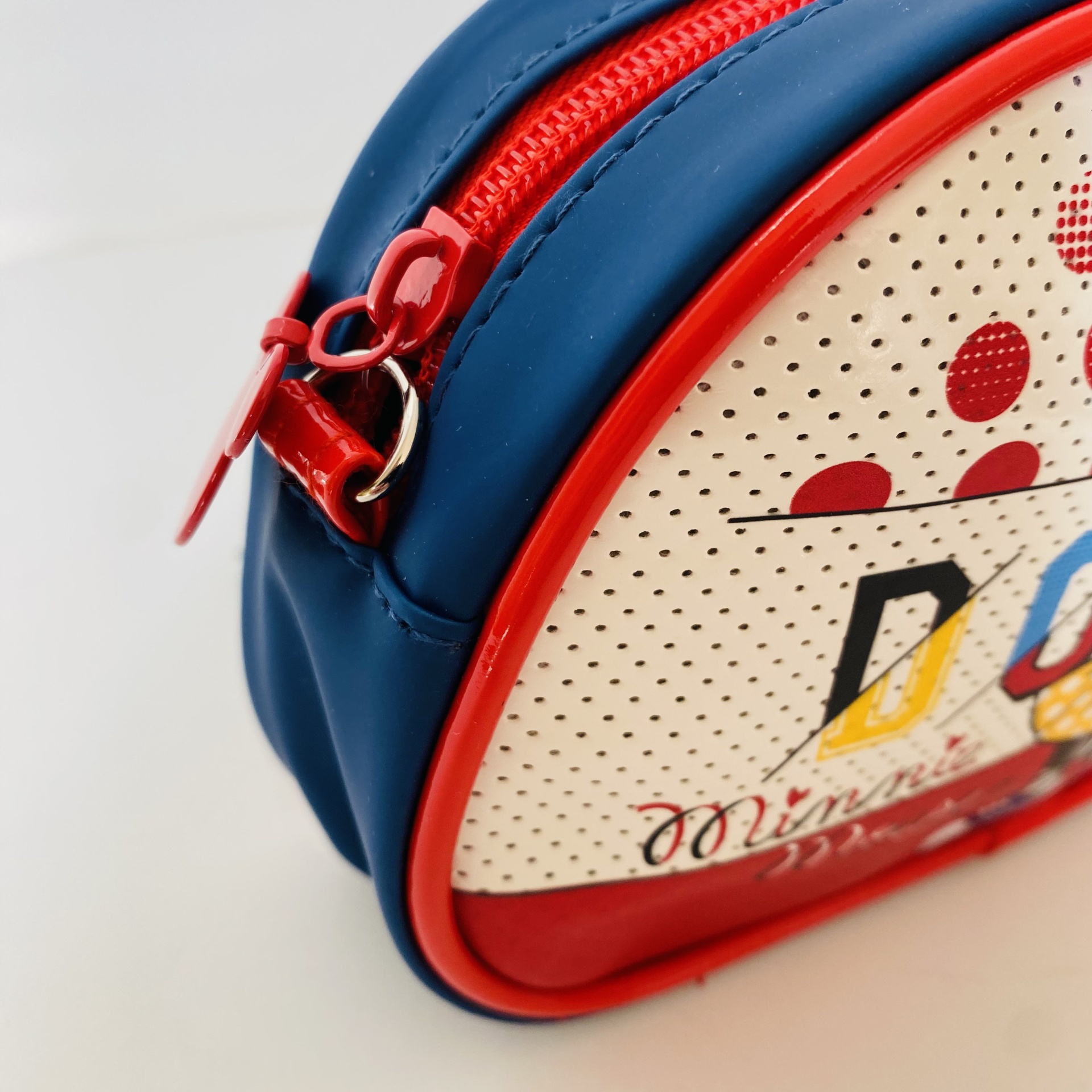 Bolsa pequena azul e branca com fecho vermelho e padrão de pontos