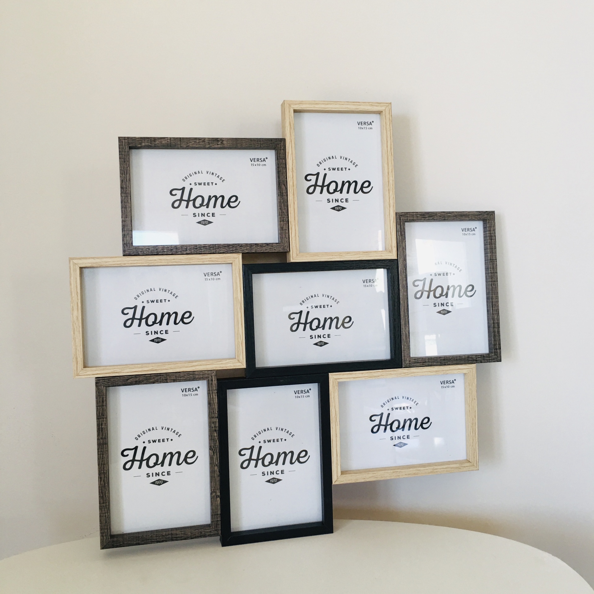 Conjunto de oito molduras de madeira com texto Home SINCE em papel interior, dispostas sobre mesa branca e parede clara.