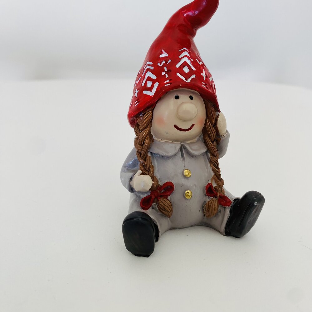 Figura de duende sentado com chapéu vermelho e casaco cinzento