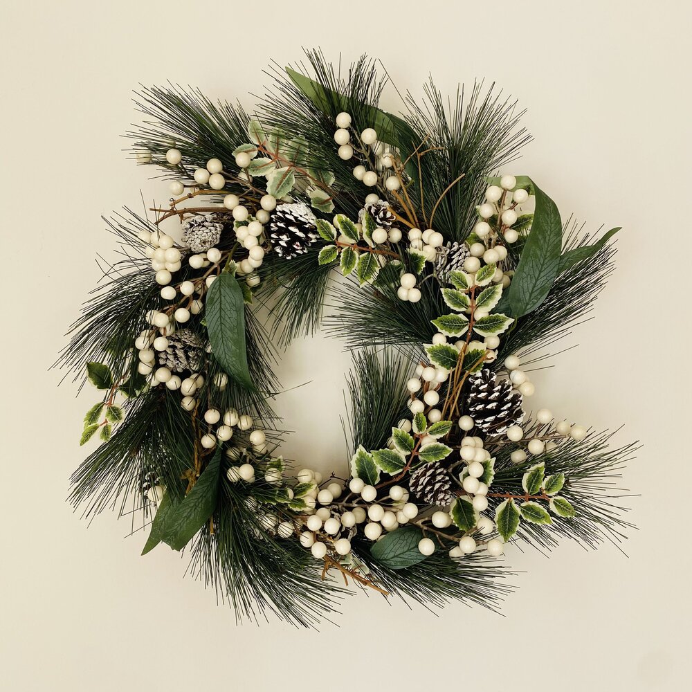 Guirlanda decorativa com folhas verdes, bagas brancas e pinhas brancas