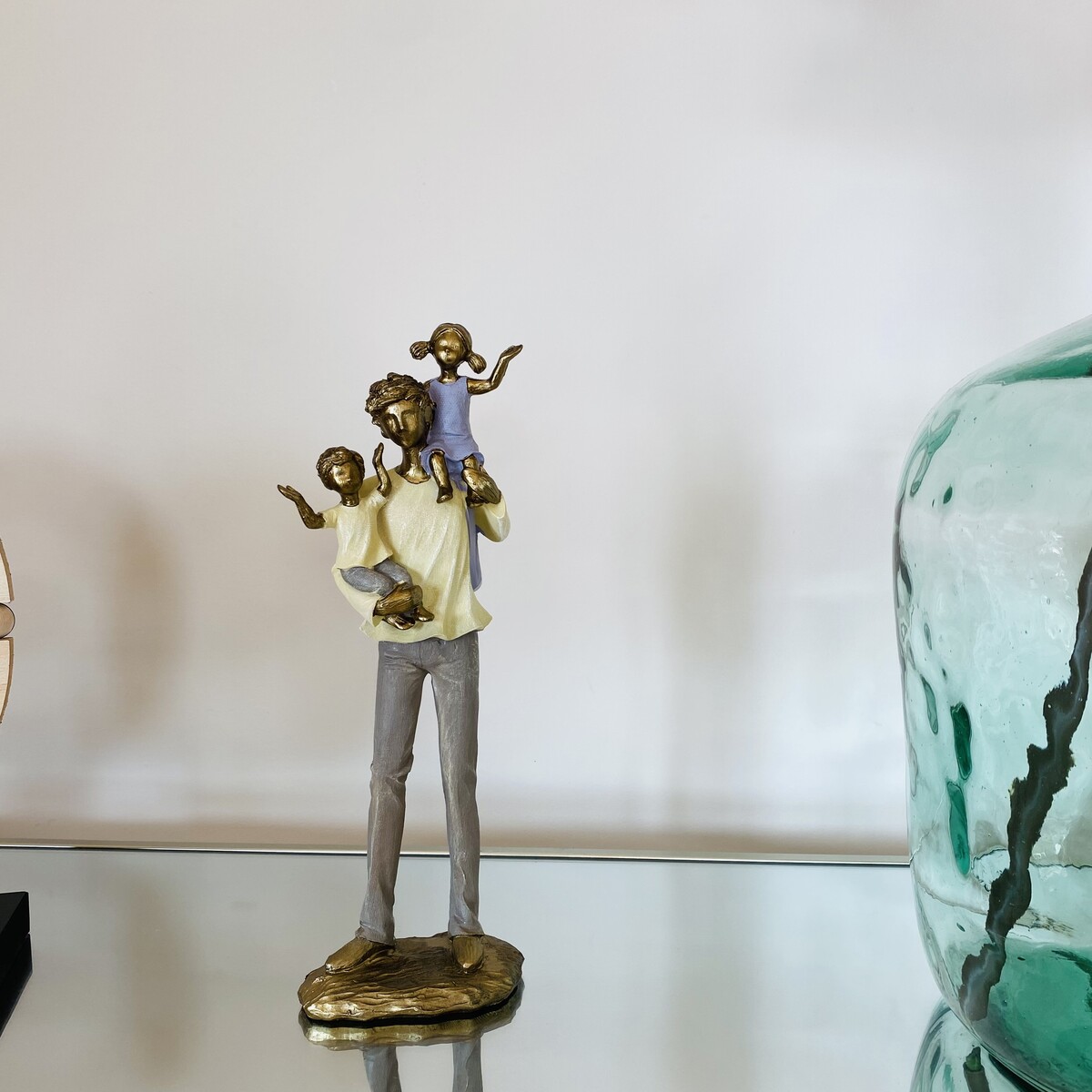 Estátua decorativa de homem com crianças em superfície espelhada