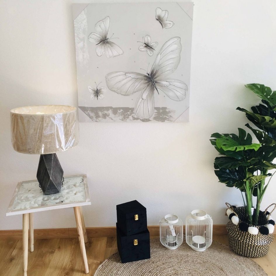 Conjunto decorativo com mesa, candeeiro, caixas pretas, lanternas, planta e quadro de borboletas