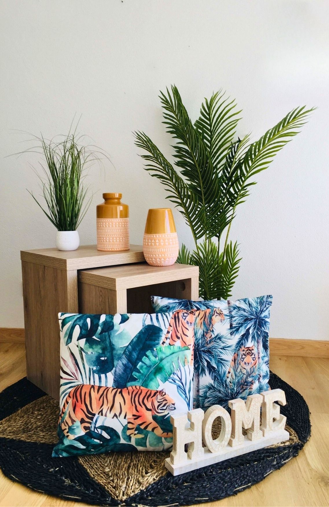 Decoração com móveis de madeira, vasos laranja, plantas verdes, almofadas estampadas e ornamento HOME
