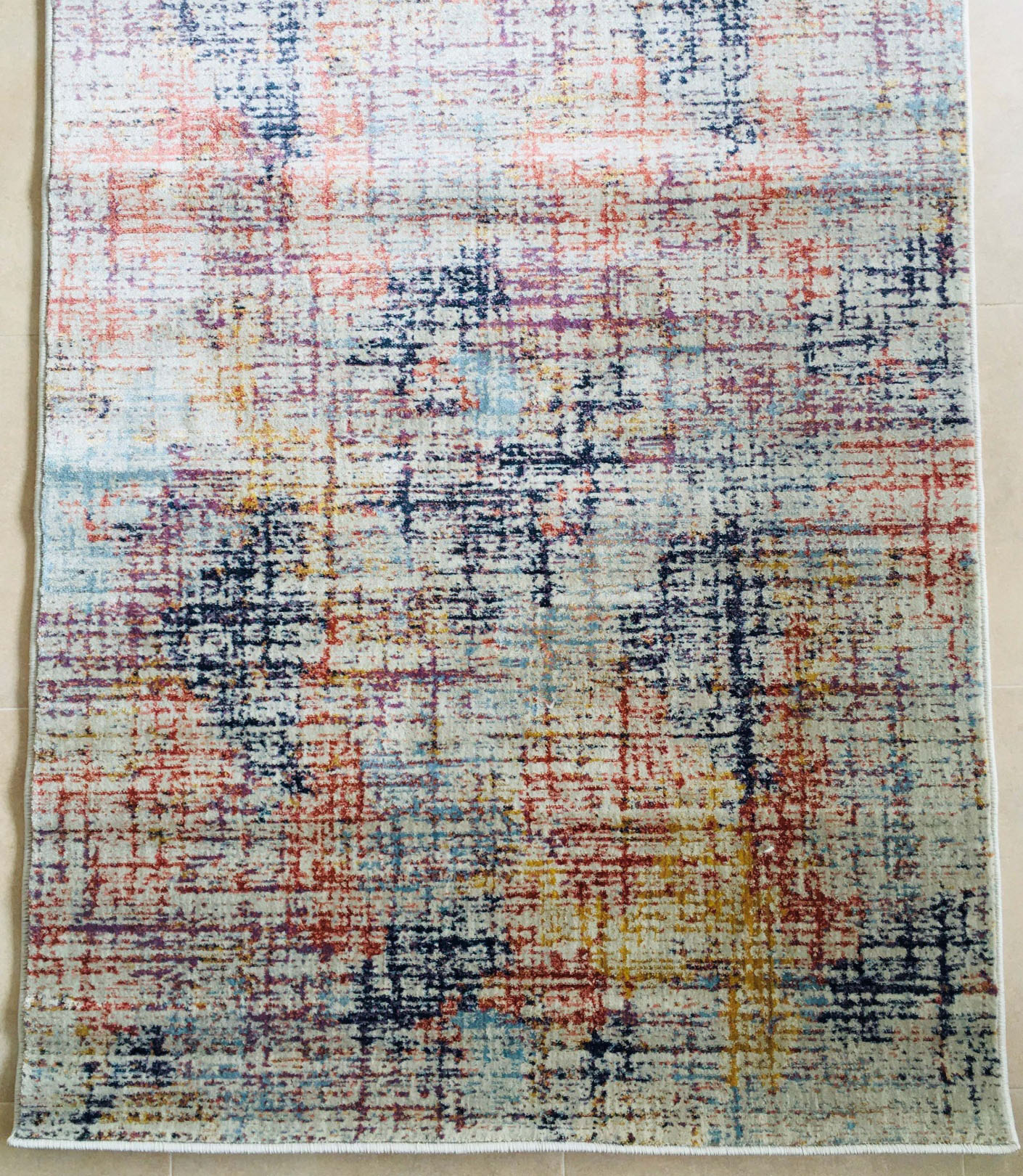 Tapete abstrato com várias cores sobre piso de azulejos claros