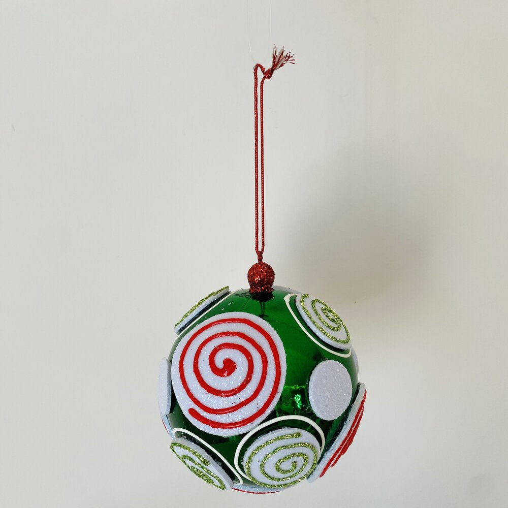 Bola de decoração natalícia verde com padrões em espiral e fio vermelho.