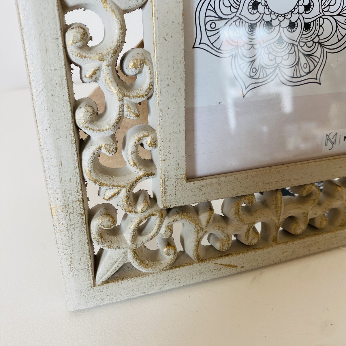 Canto de moldura decorativa branca envelhecida com desenho detalhado em papel