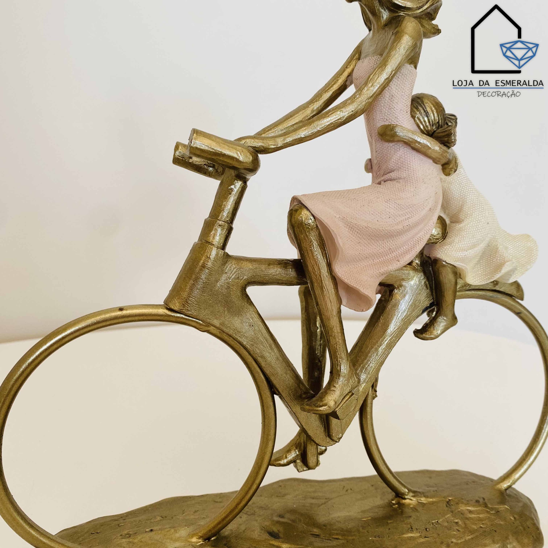 Escultura decorativa de duas mulheres numa bicicleta dourada