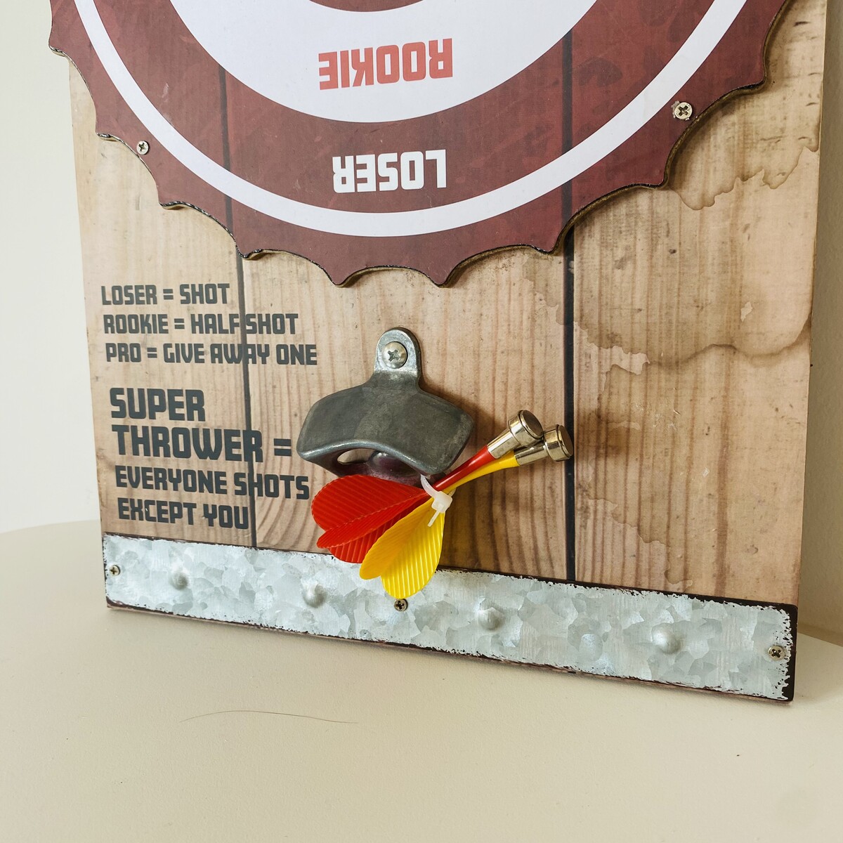 Painel de madeira com texto e abridor de garrafas com dardos coloridos