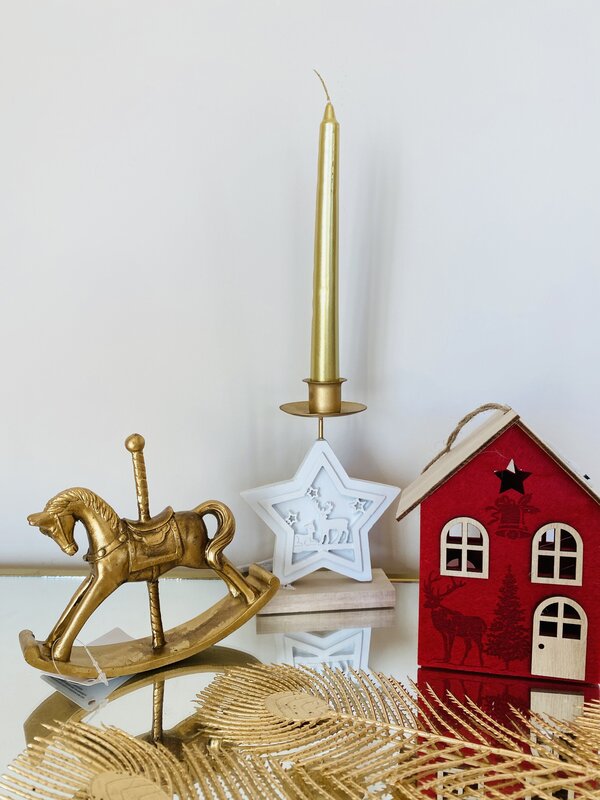 Objetos decorativos: cavalo baloiço dourado, castiçal estrela branco com vela dourada, casinha vermelha com detalhes em madeira