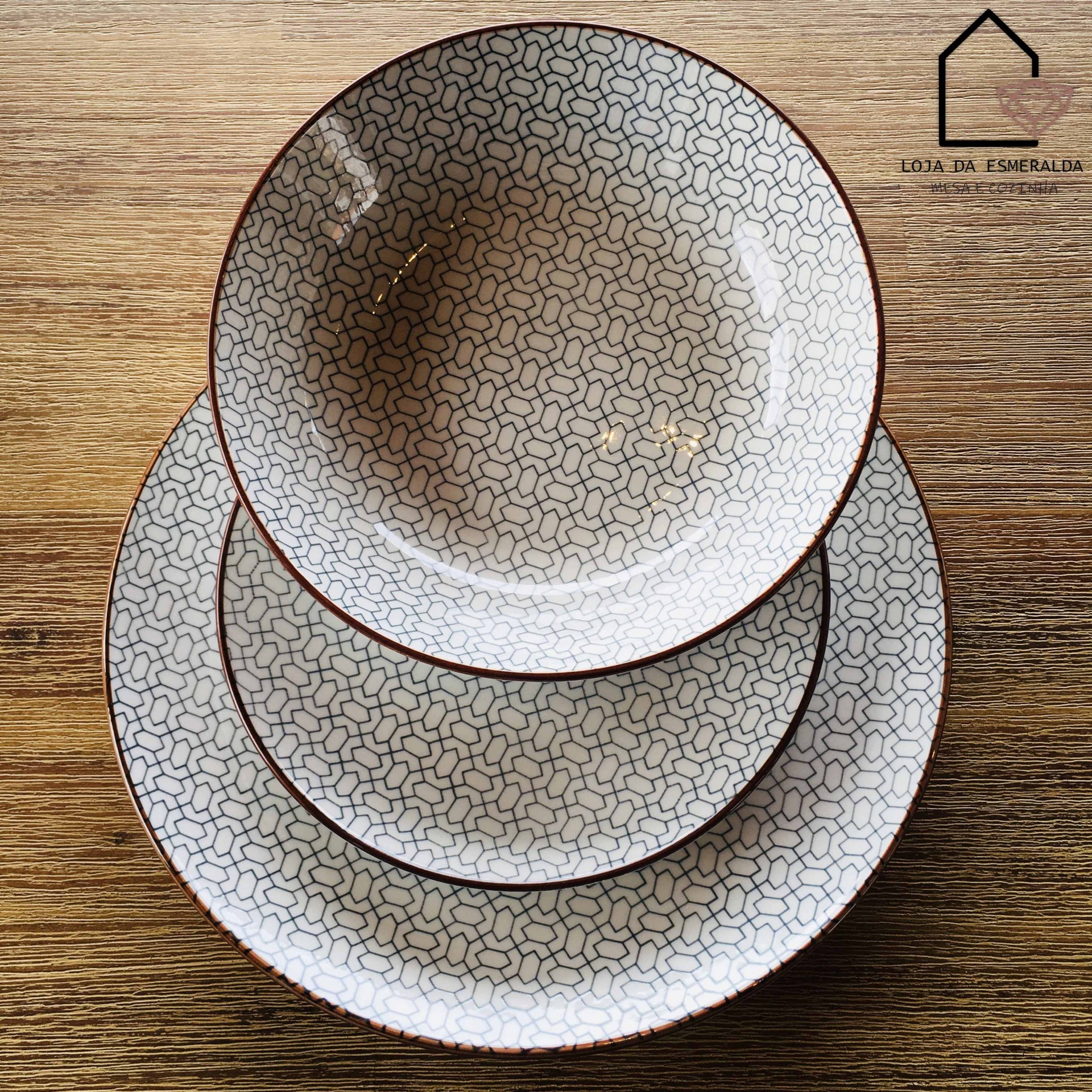 Conjunto de pratos cerâmicos brancos com padrão geométrico negro e borda castanha sobre madeira