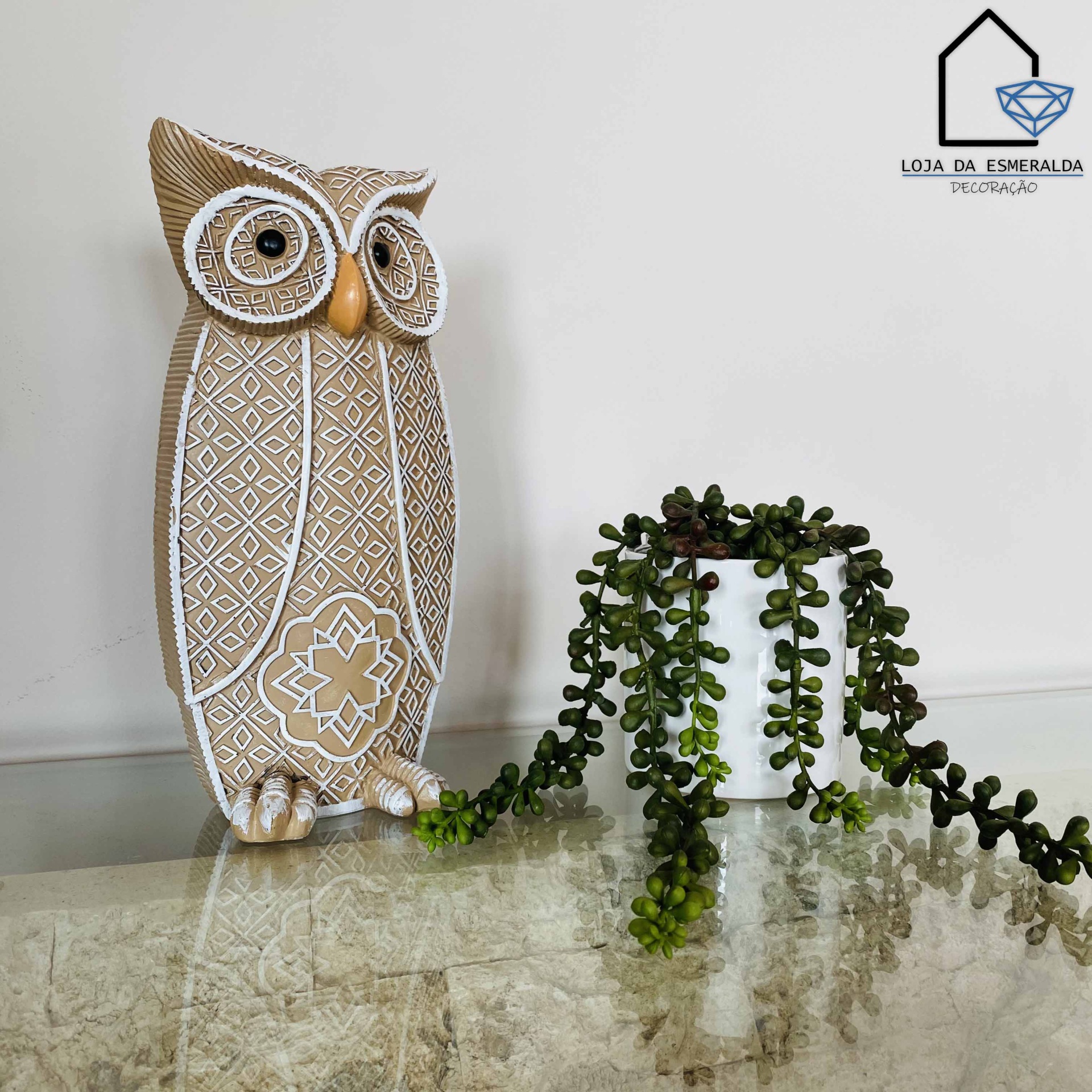 Figura decorativa de coruja bege e branca com planta artificial num vaso branco
