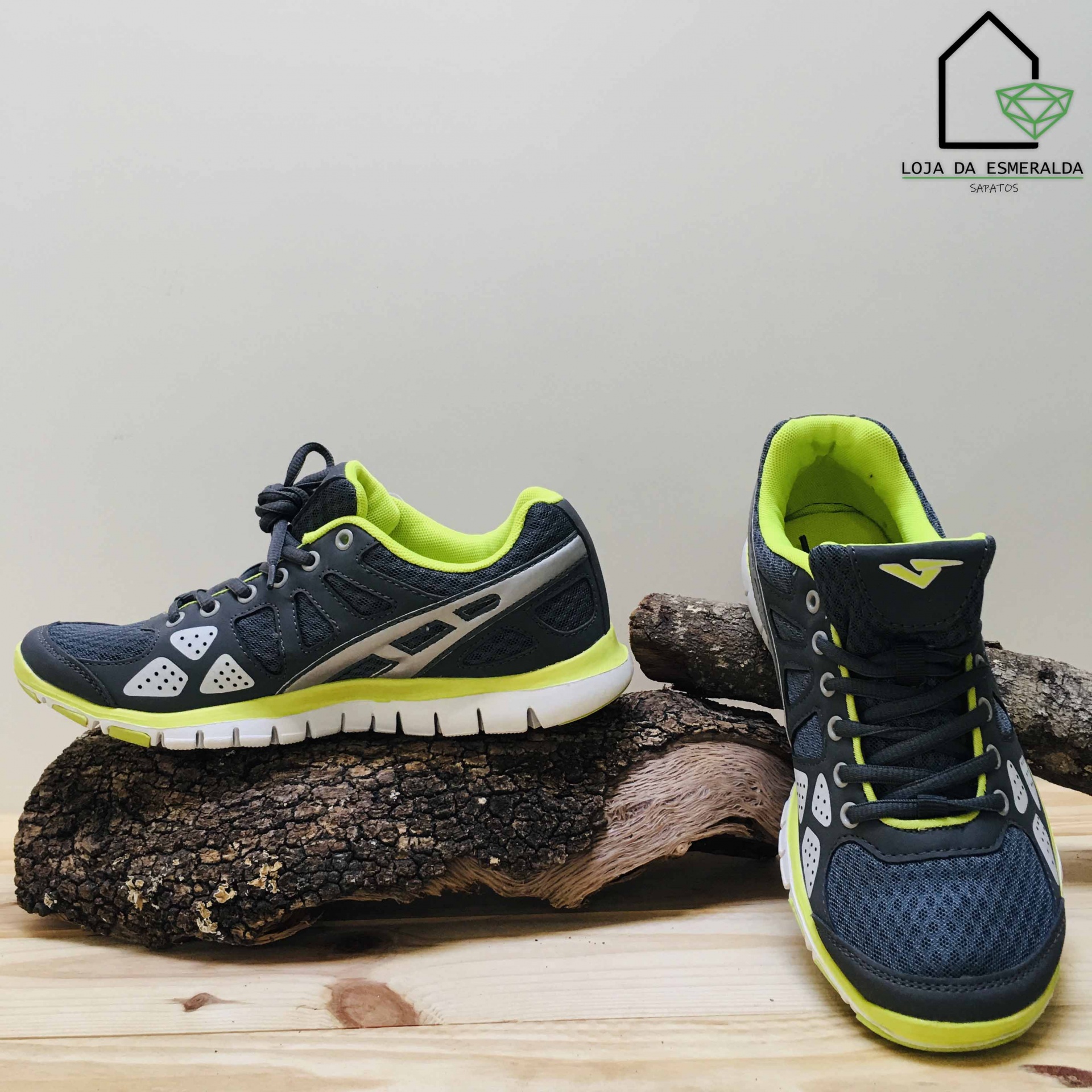 Sapatilhas desportivas pretas com detalhes verde-limão e branco sobre madeira