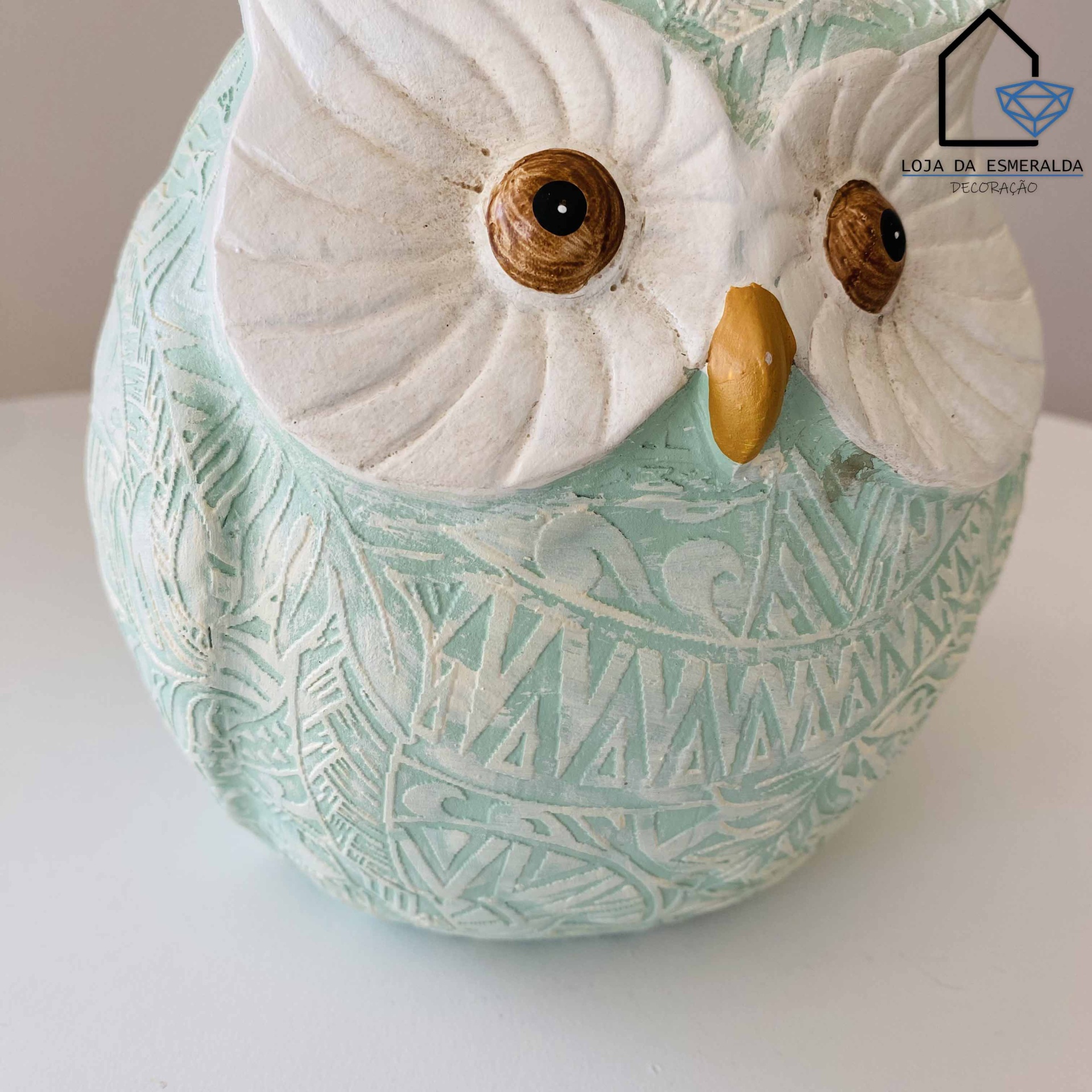 Estátua de coruja verde claro e branco com olhos castanhos