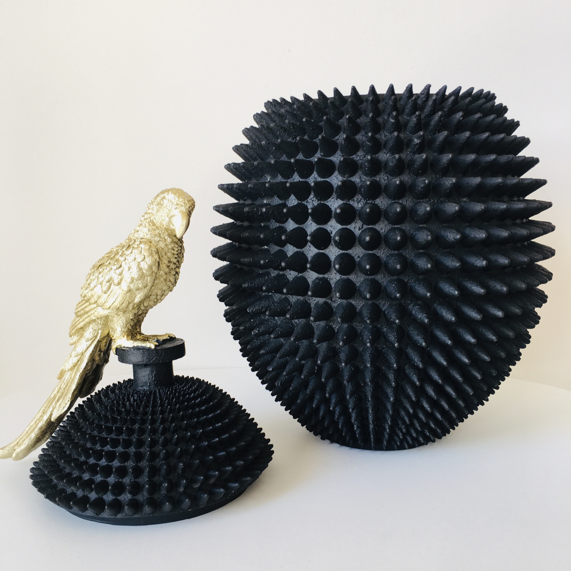 Objetos decorativos pretos espinhosos com pássaro dourado sobre fundo branco