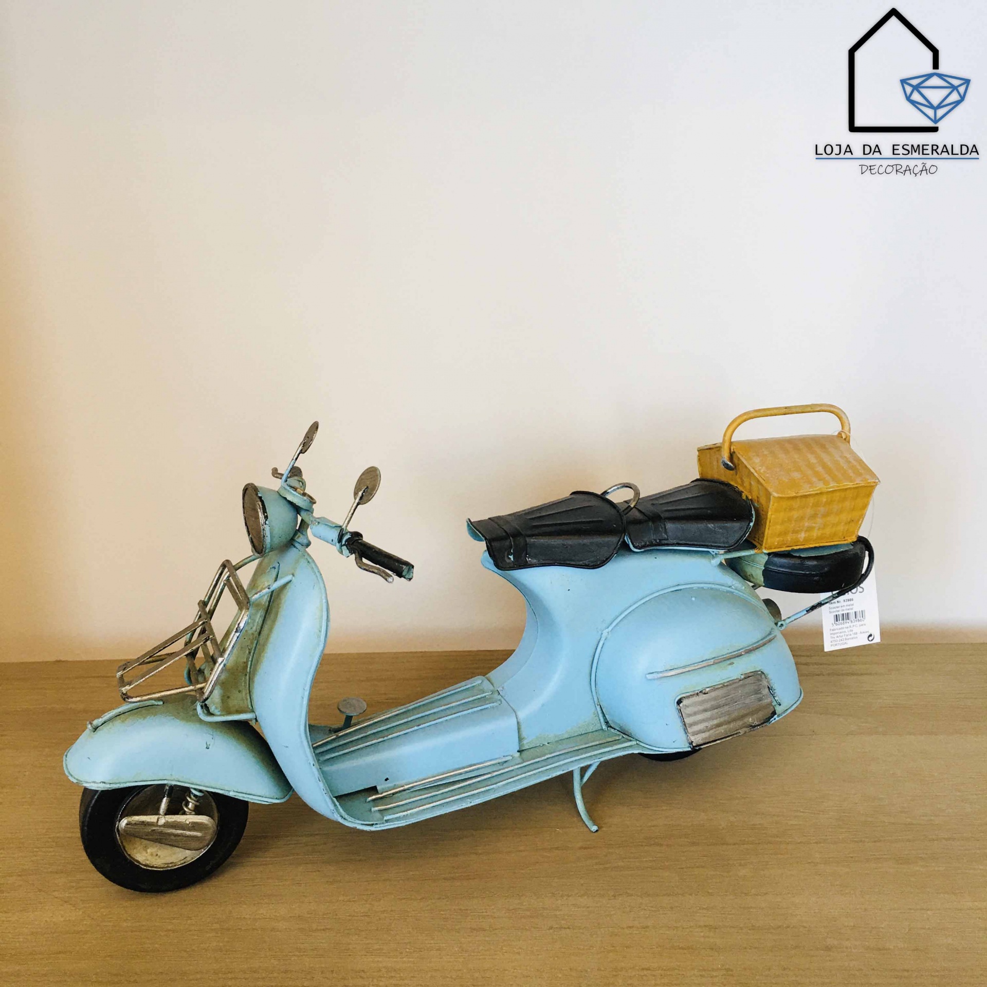 Miniatura de mota Vespa azul claro com cesto amarelo numa superfície de madeira