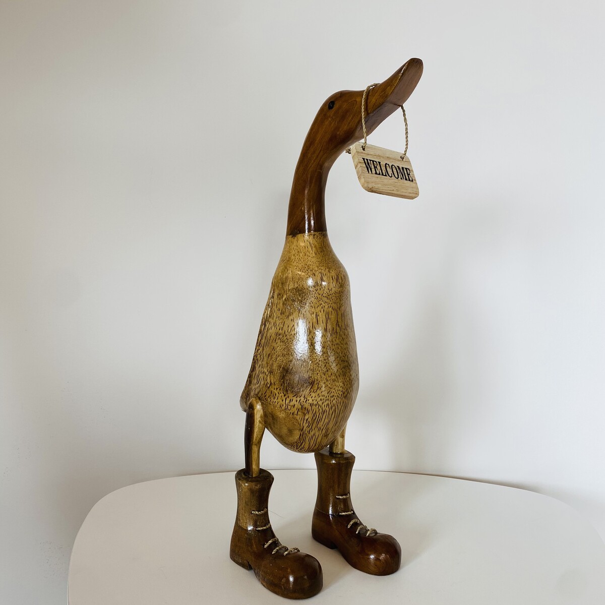 Estatueta de pato de madeira castanha com placa 'WELCOME'
