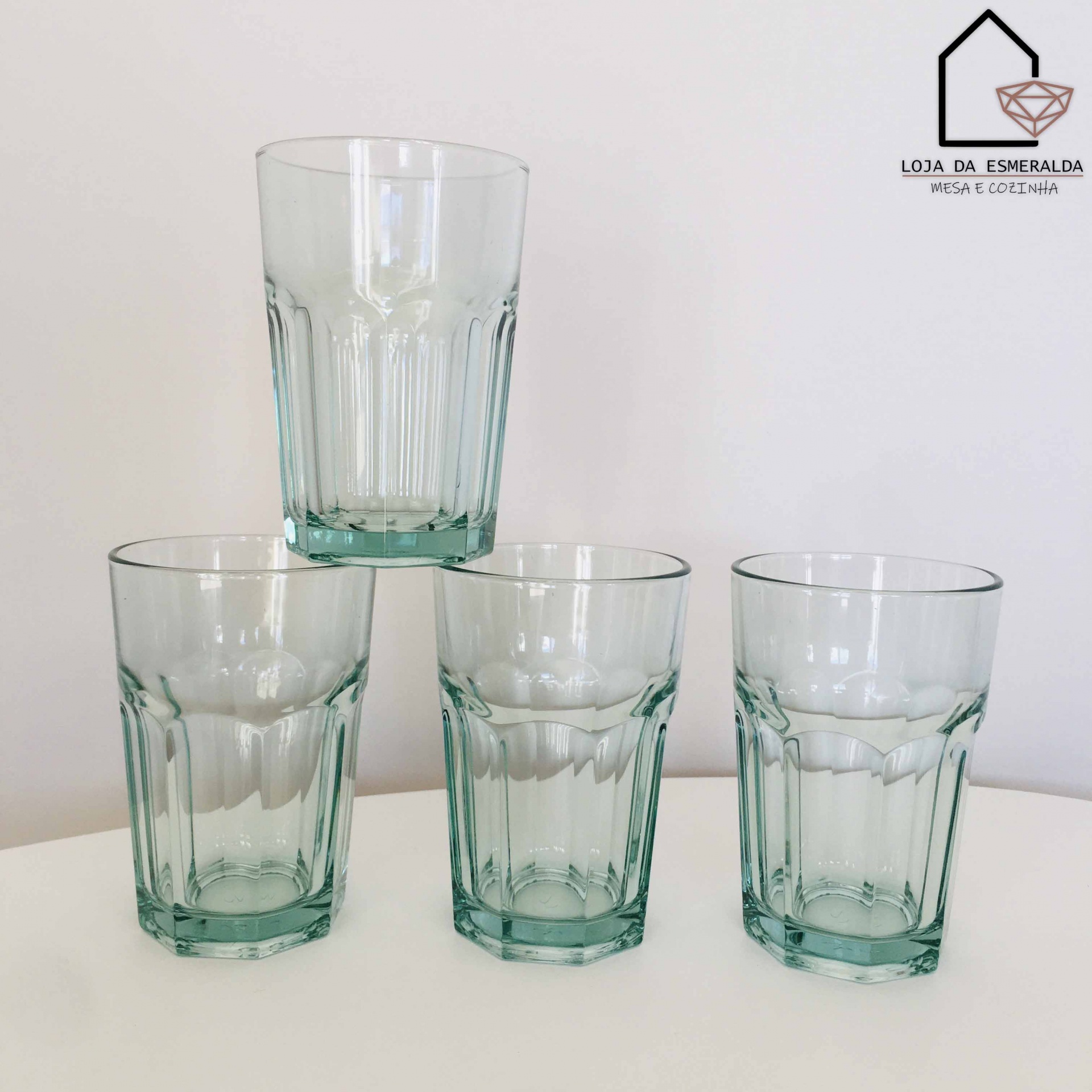 Quatro copos de vidro transparente facetados empilhados em fundo branco com logótipo da loja