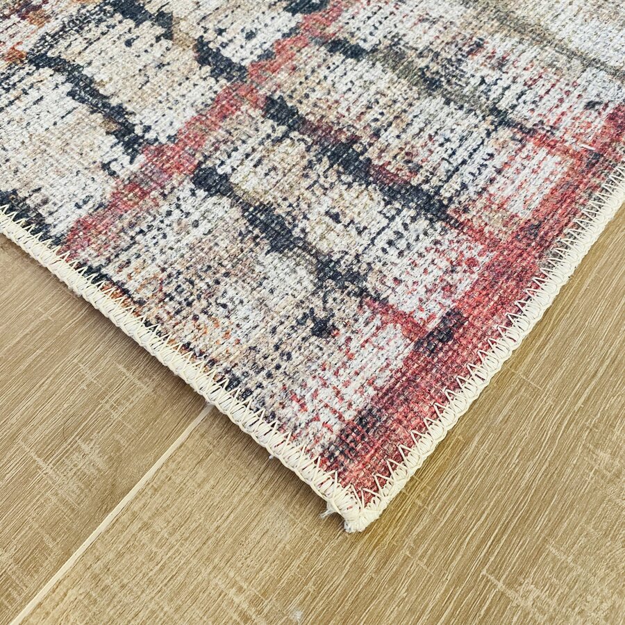 Tapete com padrão abstrato vermelho, creme e preto sobre piso de madeira clara.