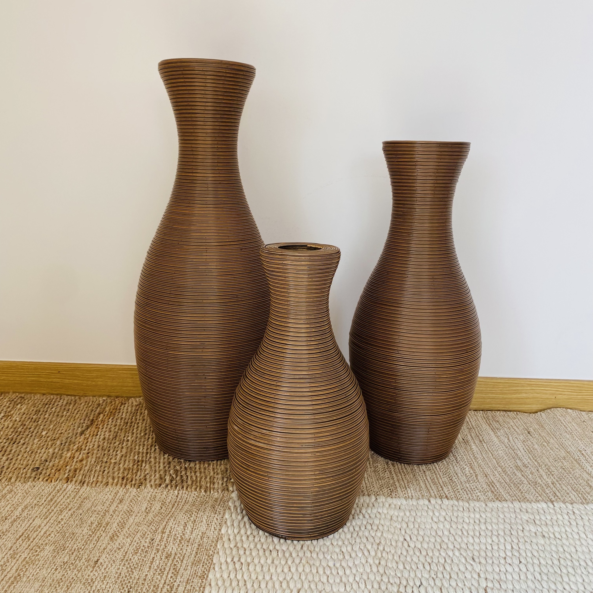 Três jarras de madeira castanha com textura circular sobre tapete bege e castanho