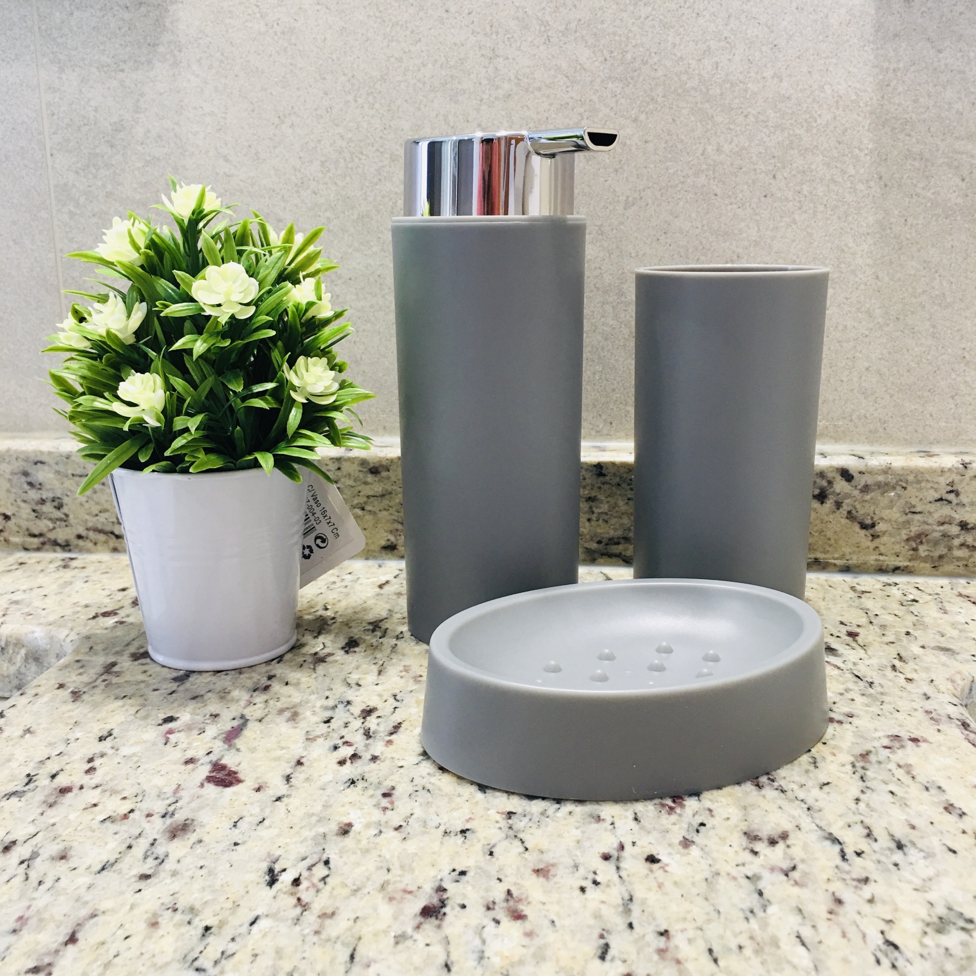 Conjunto de acessórios de casa de banho cinza com vaso de planta artificial branco sobre bancada de granito