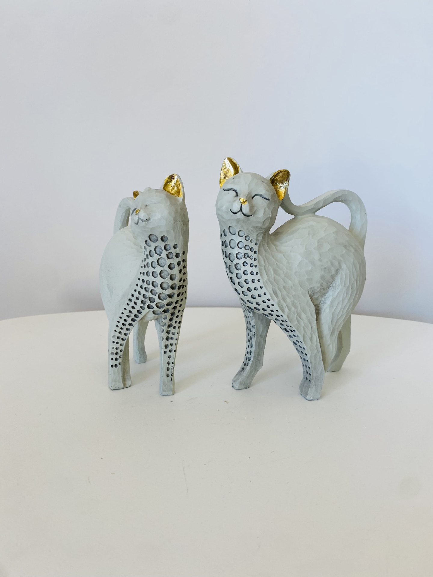 Esculturas decorativas de gatos cinza com pontos pretos e detalhes dourados