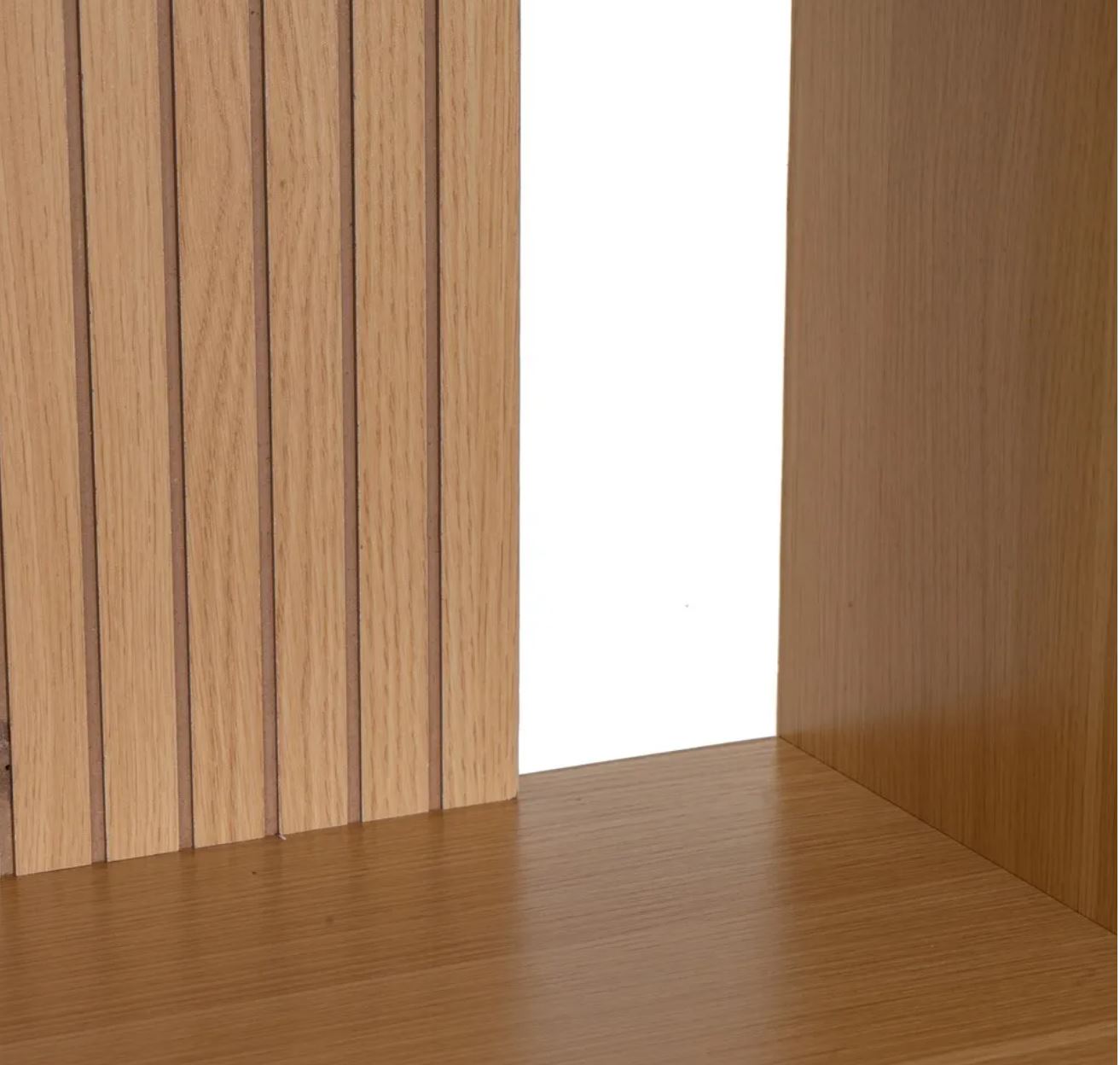 Secção de móvel de madeira clara com painéis verticais entalhados e superfícies lisas