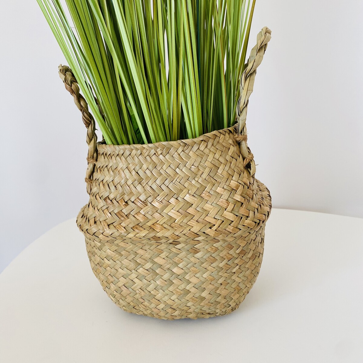 Cesto de palha natural com duas alças e plantas verdes artificiais