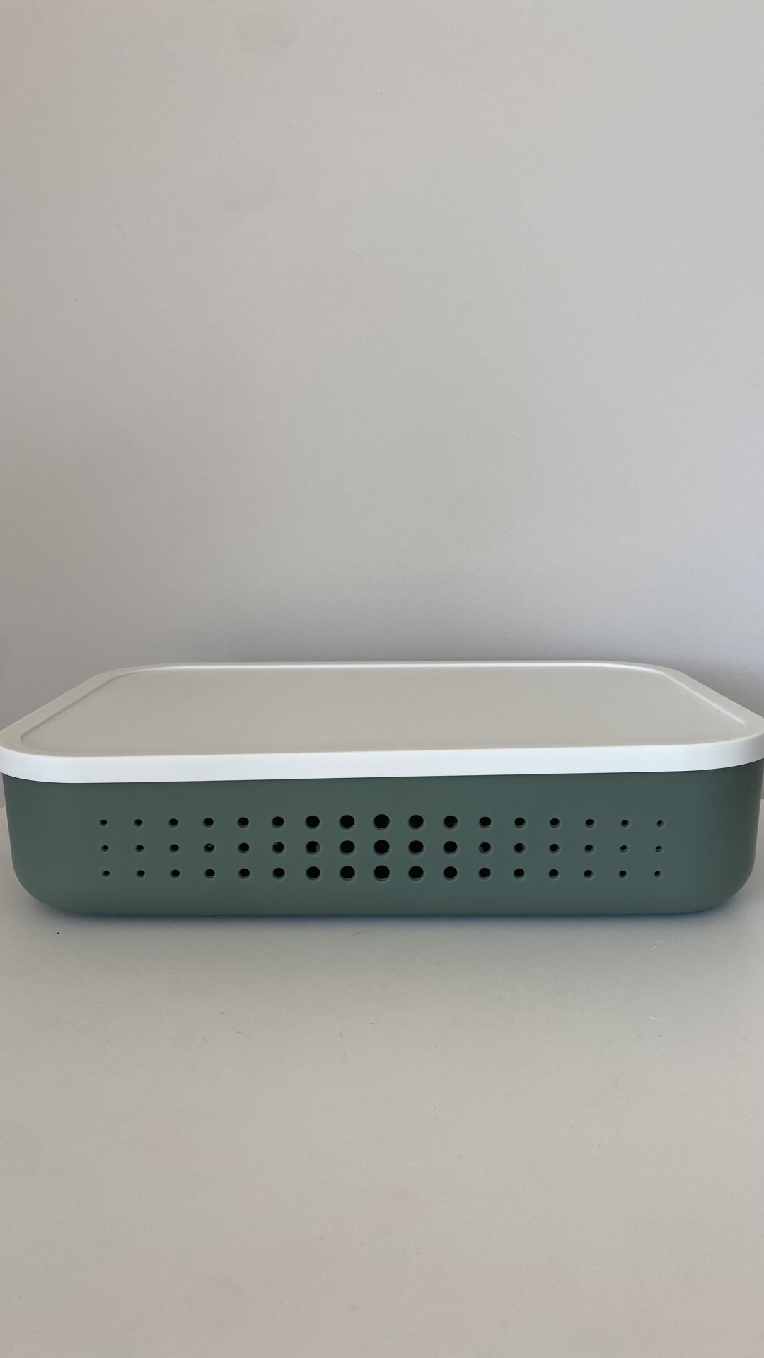 Caixa rectangular de plástico verde e branco com orifícios circulares