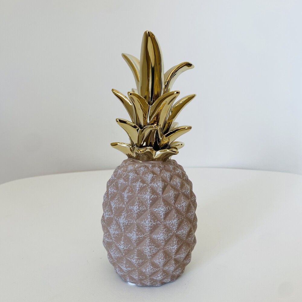Ananás decorativo prateado com folhas douradas em mesa branca