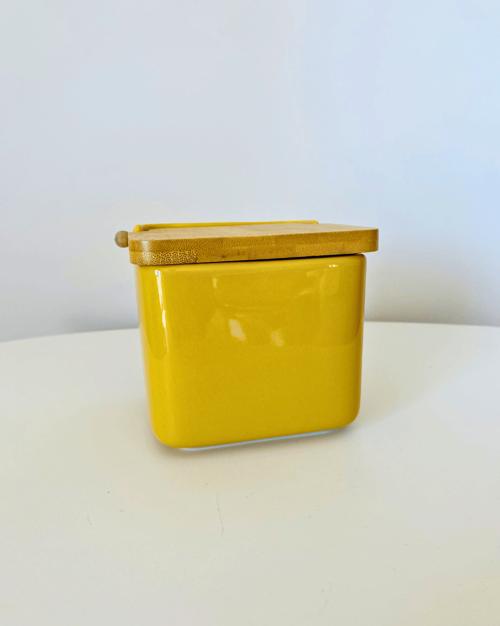 Recipiente amarelo com tampa e colher de madeira