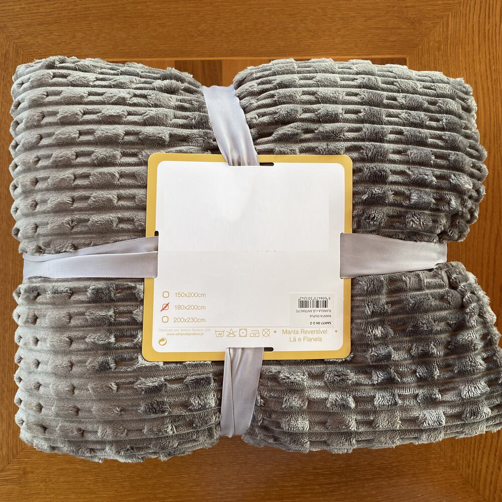 Manta cinzenta texturizada embalada sobre fundo de madeira