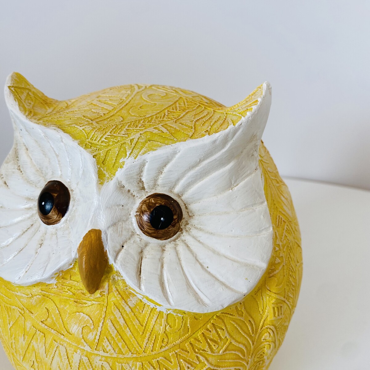 Figura decorativa de coruja amarela com detalhes brancos e olhos castanhos