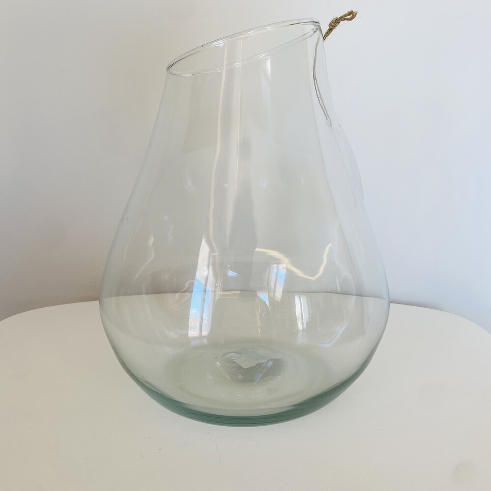 Jarro de vidro transparente com cordão na borda, sobre superfície branca