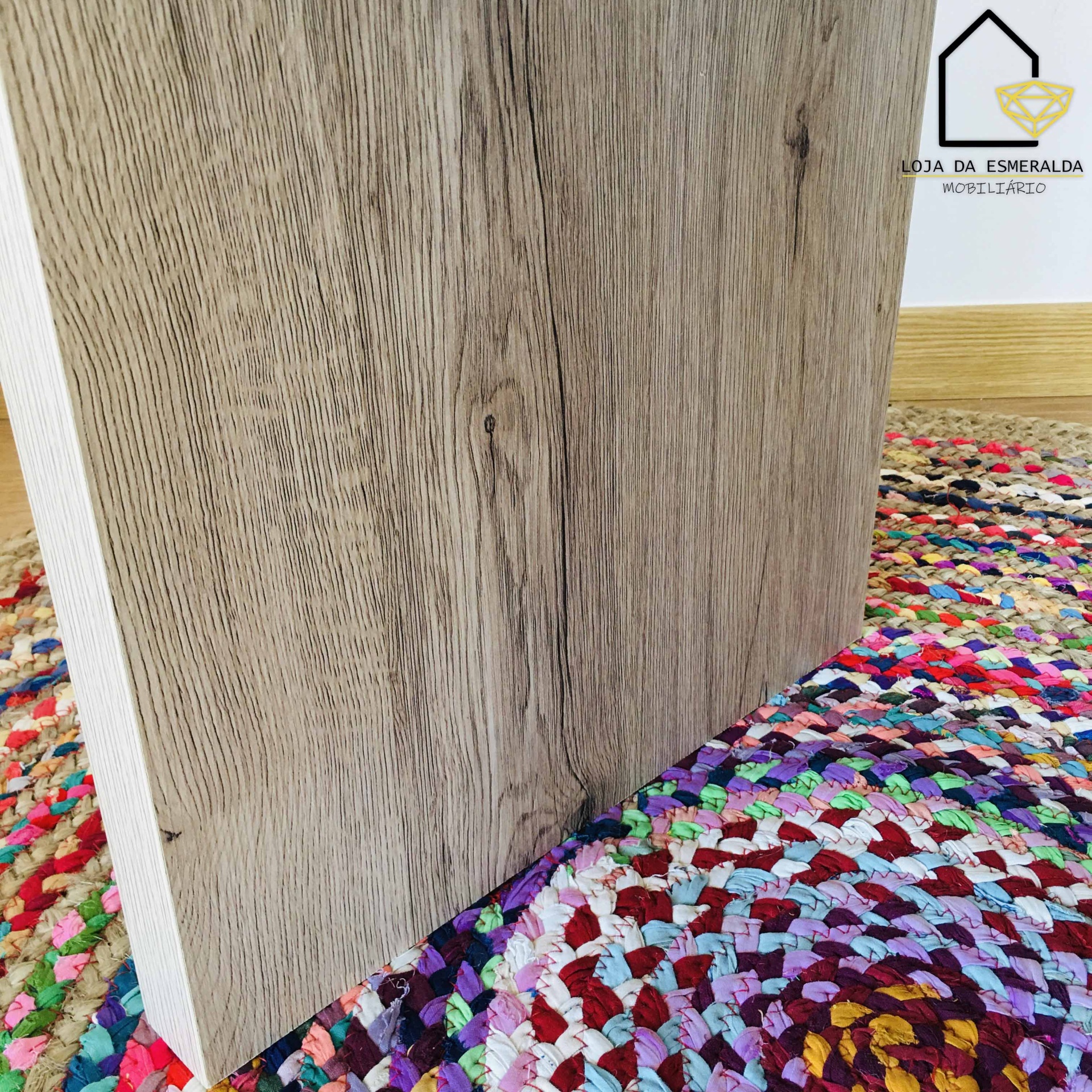 Mesa de madeira clara sobre tapete colorido trançado em ambiente interior