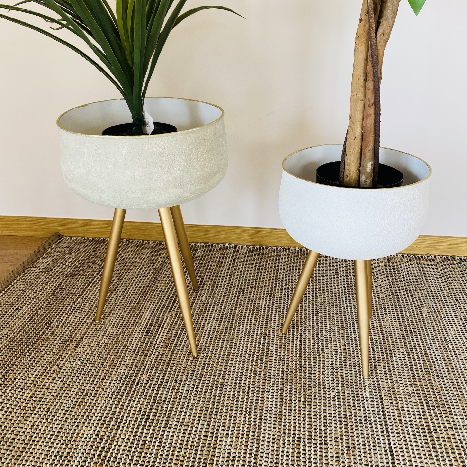 Dois vasos modernos elevados com plantas sobre tapete de fibras naturais