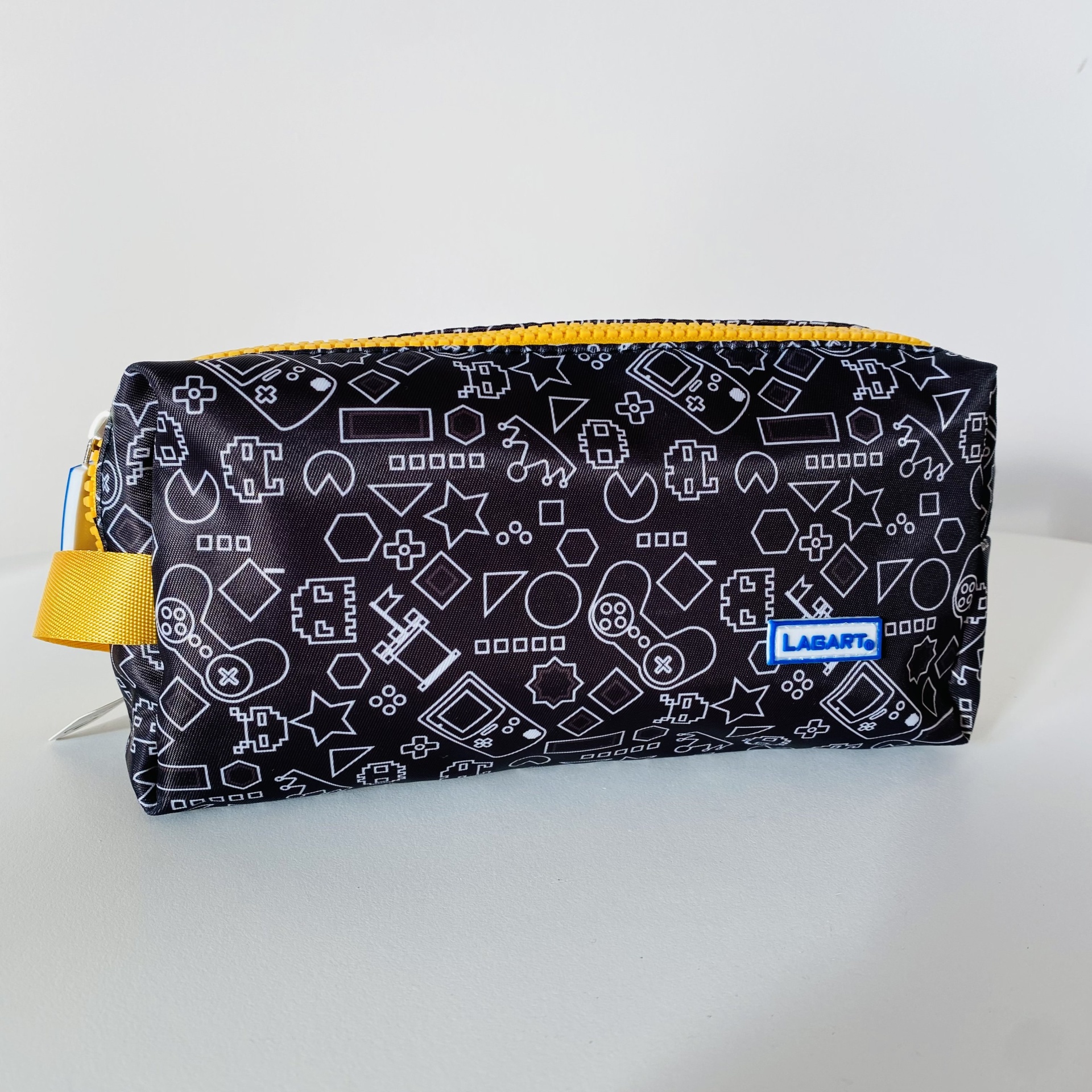 Necessaire preta com padrão branco de desenhos de videojogos e fecho amarelo.