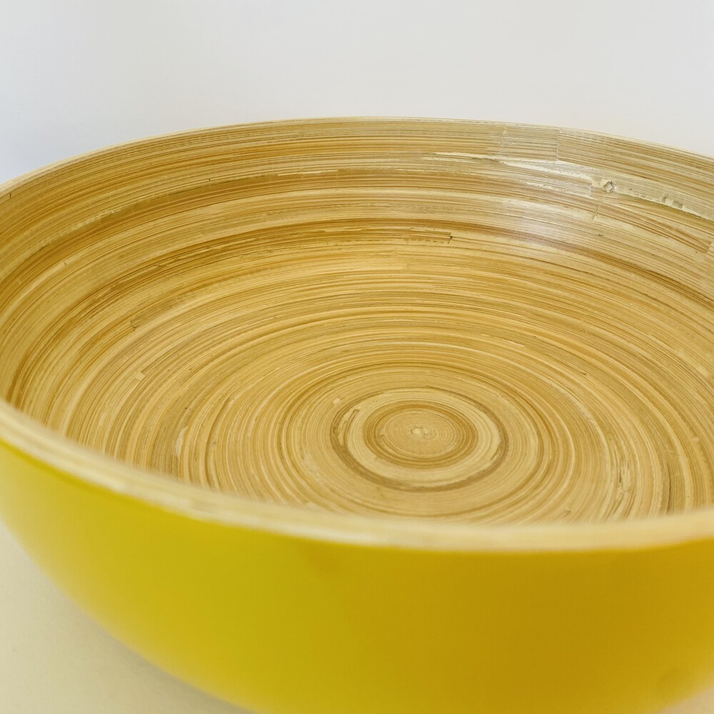 Taça amarela com interior de madeira clara e textura circular.